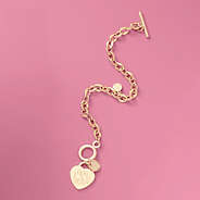monogrammed heart bracelet in gold flatlay on pink