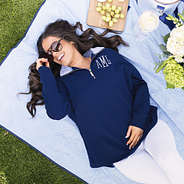 girl wearing monogrammed quarter zip sweatshirt in navy blue shells on picnic blanket
