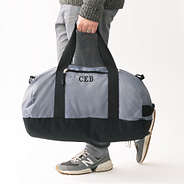 man carrying charcoal and black monogrammed packable travel bag