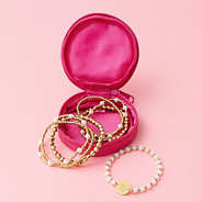 hot pink travel jewelry case with gold beaded bracelet stack