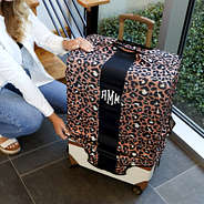 securing monogrammed cheetah luggage cover over suitcase