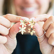 Double flower earrings held in front of girl