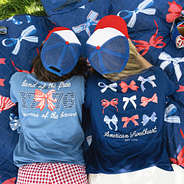 women laying on picnic blanket wearing light navy and bows america t shirt