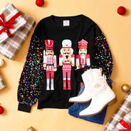 nutcracker sweatshirt flatlay with jeans and boots