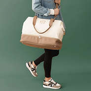 ivory canvas weekender on shoulder with green background