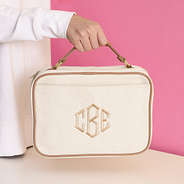 ivory travel toiletry bag in hand with pink background