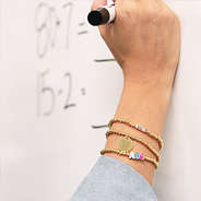 teacher writing on white board with monogrammed gold teacher bracelet beaded stack