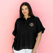 monogrammed top in black in front of pink paper