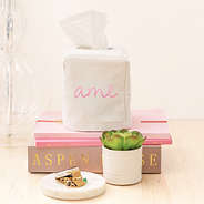 monogrammed tissue box on bedside table with books