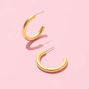 brushed hoop gold earrings on pink background