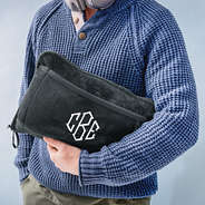man holding monogrammed charcoal travel blanket pillow