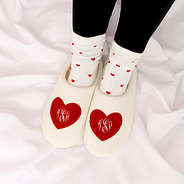 heart socks with monogrammed slippers on white sheet