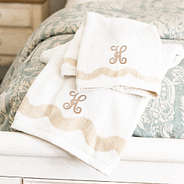 bath towel set on bed with tan interlocking inital
