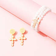 monogrammed cross earrings and stretchy cross bracelet on pink paper