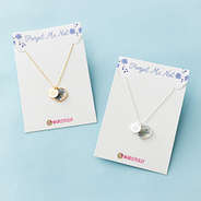 gold and silver forget me not necklace on cards on blue paper