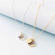 silver and gold forget me not necklaces on blue paper roll