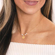 girl wearing gold monogrammed gold pearl necklace