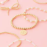 gold pearl bow monogrammed bracelet stack scattered