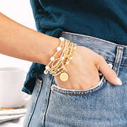 personalized pearl bow bracelet stack in gold on wrist