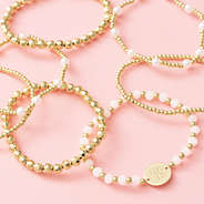 gold pearl beaded monogrammed bracelets scattered