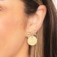 gold bow dangle earrings in ear