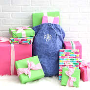 monogrammed gift sack with presents in front of brick wall