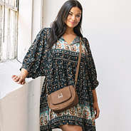 girl with monogrammed crossbody bag in brown over shoulder