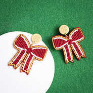 crimson gameday bow earrings on green background