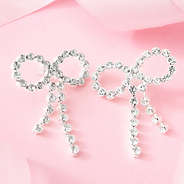 silver rhinestone bow earrings on pink background