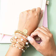 gold twisted knot bracelet on arm with bow bracelet