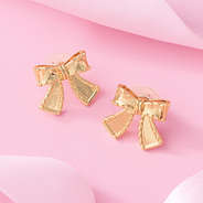 gold bow stud earrings on pink background