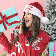 girl wearing red monogrammed santa hat with present
