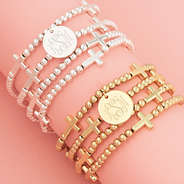 close up of monogrammed silver and gold cross bracelet stacks