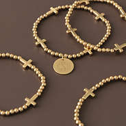 gold monogrammed cross bracelet stack scattered