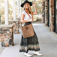 girl carrying monogrammed whipstitch brown purse over shoulder with midi skirt