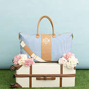 navy seersucker weekender and vintage suitcase on grass and blue