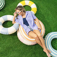 girl wearing lavender monogrammed fishing shirt on pool floaties in grass