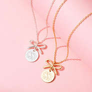 Gold and silver bow necklaces on pink