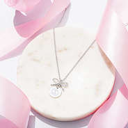 Silver bow necklace on marble with ribbon