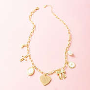 gold charm necklace on pink background