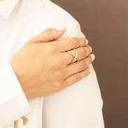 gold adjustable criss cross ring on hand with white shirt