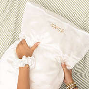 white satin pillowcase and scrunchie on green stripe sheets