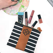 monogrammed striped zip pouch with lotion and lip gloss on desk