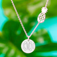 silver monogrammed pineapple necklace with palm leaves in background