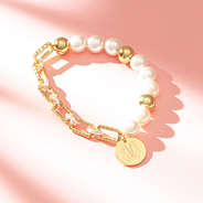 gold pearl bracelet on pink background with shadows