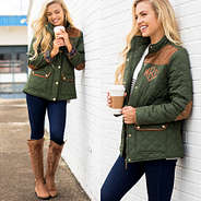 olive monogrammed barn coat on girl leaning on white brick wall