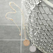 monogrammed pave necklaces on glass table