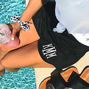 girl sitting by the pool wearing monogrammed athleisure shorts holding starbucks smoothie