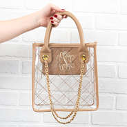 monogrammed clear tote in front of white brick wall