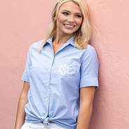 short sleeved monogrammed oxford top with white shorts in front of pink wall